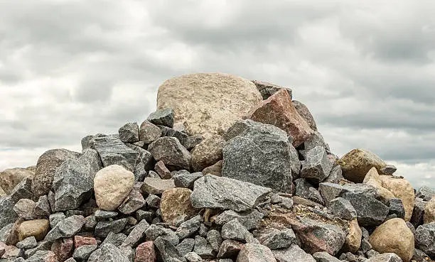 Photo of pile of huge rocks and boulders under dark grey sky