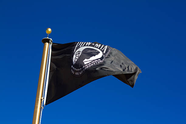 pow-mia bandeira voando no céu azul brilhante - prisioneiro de guerra - fotografias e filmes do acervo