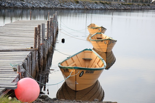 Cape Sable Island, Canada - September 20, 2014: Boats and wharf at Cape Sable Island, Nova Scotia, Canada. three dorys in a row tied to a pier, ocean very calm