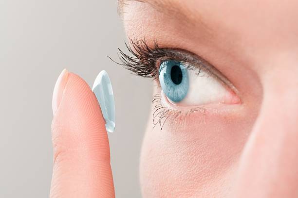 woman inserting a contact lens in eye. - lins ögonglob bildbanksfoton och bilder