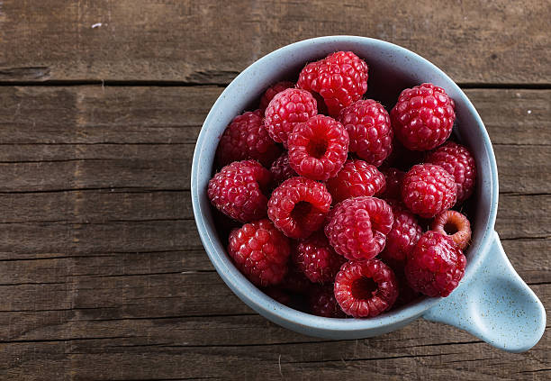 istock Ripe fresh raspberries in bowl on wooden rustic background 507173188