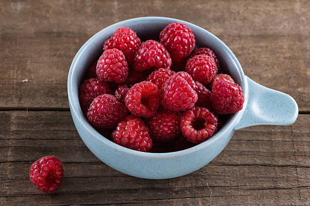 istock Ripe fresh raspberries in bowl on wooden rustic background 507173412