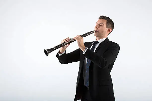 the young musician on a gray background plays the clarinet