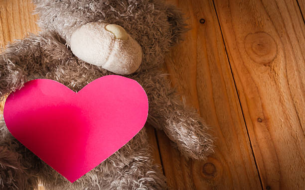 istock Teddy bear with red heart on wood background 507174968