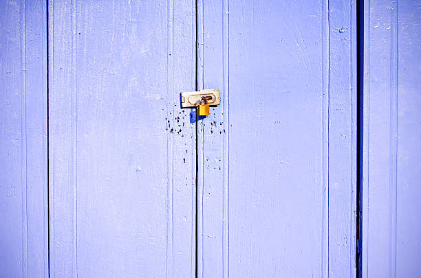 istock Old rusted lock on blue wooden doors 507176016