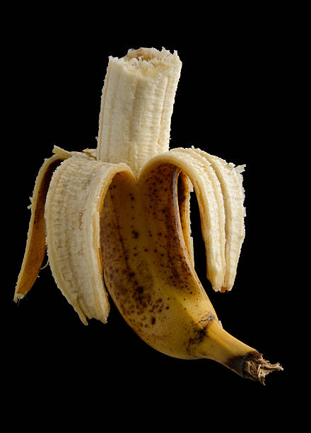 istock Half peeled spotted banana isolated on black 507177012