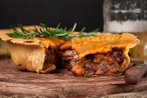 Homemade australian meat pie on the wooden table closeup with copy space, rustic style