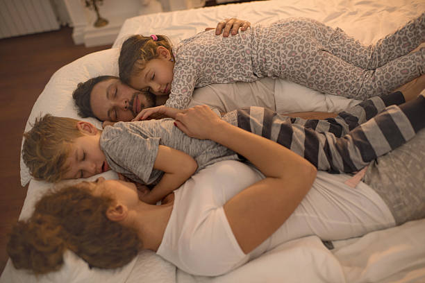 Young family taking a nap together on a bed.