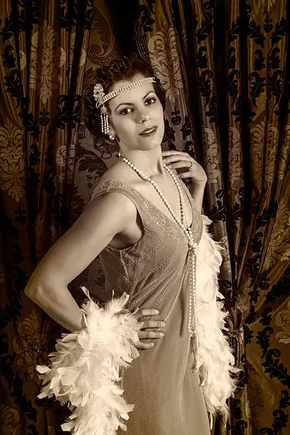 Beautiful vintage 1920s lady wearing a headband and white feather boa