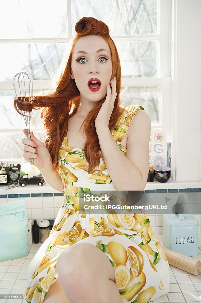 Portrait of Beautiful woman Portrait of a surprised young woman with hair tangled in whisk sitting on kitchen counter 20-24 Years Stock Photo