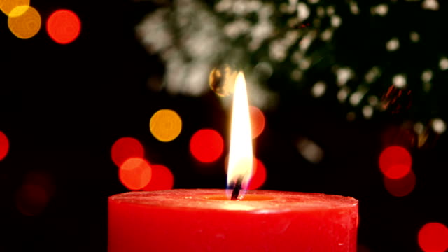 Two red candles with christmas decorations on black, bokeh, light, garland, cam moves to the right