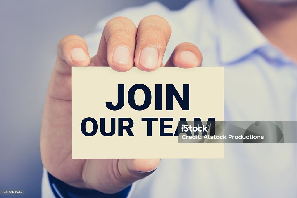 JOIN OUR TEAM, message on the card JOIN OUR TEAM, message on business card shown by a man Help Wanted Sign Stock Photo