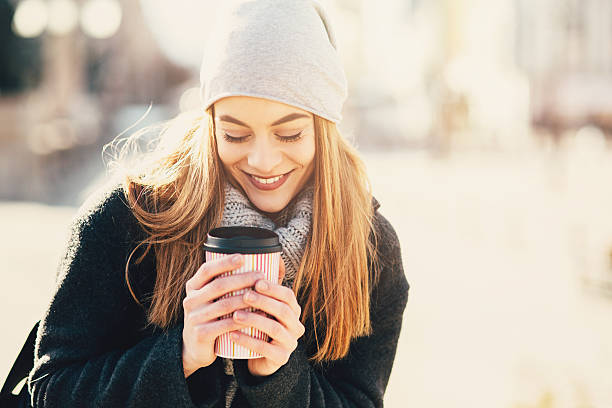 A young woman drinking coffee outdoors.