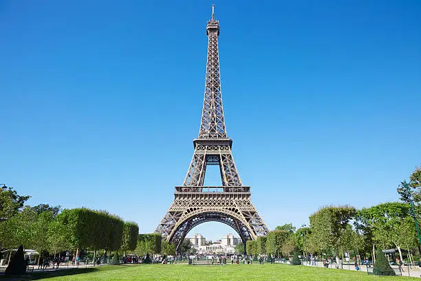Eiffel tower, sunny summer day with blue sky and green Field of Mars in Paris