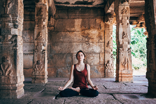 Woman doing yoga in Vishnu temple in Hampi, India 