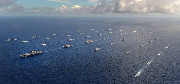 Sea Power Forty-two ships and submarines representing 15 international partner nations manuever into a close formation during Rim of the Pacific (RIMPAC) Exercise 2014. Twenty-two nations, more than 40 ships and six submarines, more than 200 aircraft and 25,000 personnel are participating in RIMPAC exercise from June 26 to Aug. 1, in and around the Hawaiian Islands and Southern California. The world's largest international maritime exercise, RIMPAC provides a unique training opportunity that helps participants foster and sustain the cooperative relationships that are critical to ensuring the safety of sea lanes and security on the world's oceans. RIMPAC 2014 is the 24th exercise in the series that began in 1971. military ship photos stock pictures, royalty-free photos & images