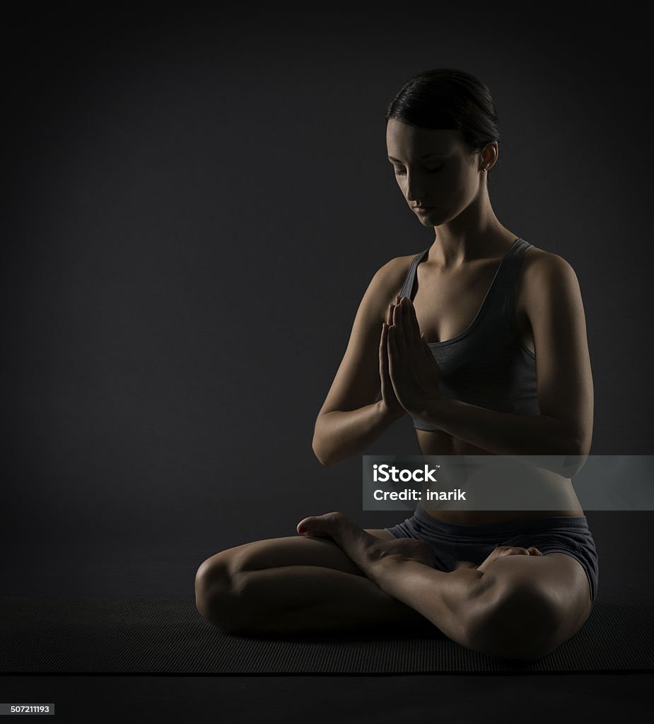 Yoga woman meditate sitting in lotus pose exercise Yoga woman meditate sitting in lotus pose. Silhouette of exercise girl over black background. Adult Stock Photo
