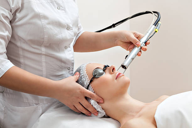 Woman in healthy spa salon Woman lying on a table with protect glasses on eyes getting a laser skin treatment in healthy beauty spa salon laser stock pictures, royalty-free photos & images