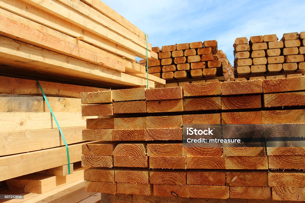 Image of wood planks / sawmill posts in timber yard piles Photo showing some huge piles of wooden planks and fence posts, freshly sawn up in a sawmill and piled in the timber yard, ready to be sold to the general public. Timber Stock Photo