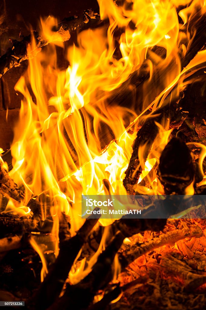 Wood fire burning logs and branches Closeup of a wood fire with flames burning branches and logs. Vertical image. Black Color Stock Photo