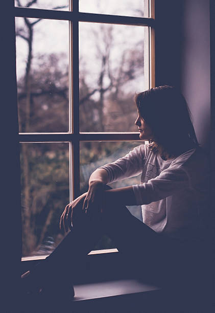 istock Young attractive woman, sitting on a window, looking outside 507214782