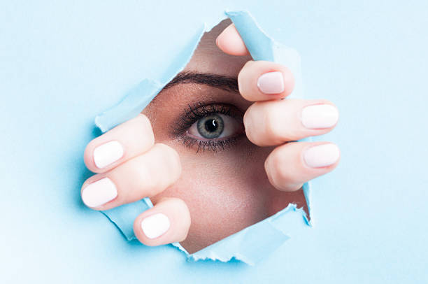 istock Woman blue eye with mascara looking thru ripped board 507215458