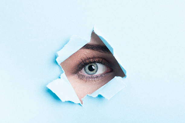 istock Female eye with mascara looking thru torn cardboard 507215632