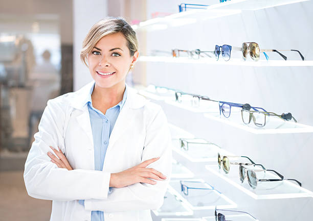 Optician selling glasses at the optics Happy optician selling glasses and looking at the camera smiling optical instrument stock pictures, royalty-free photos & images