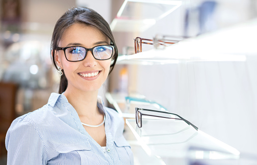 Beautiful Latin American woman buying glasses at the optician's shop - vision concepts