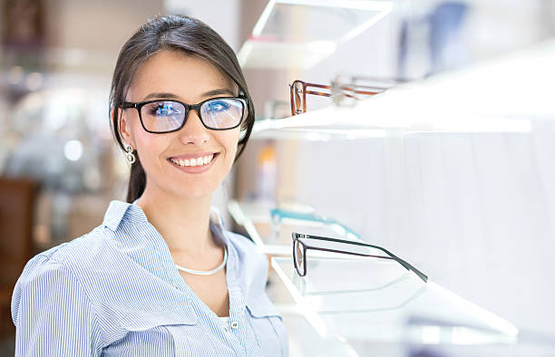 woman buying glasses at the optician's shop - patient happiness cheerful optometrist imagens e fotografias de stock