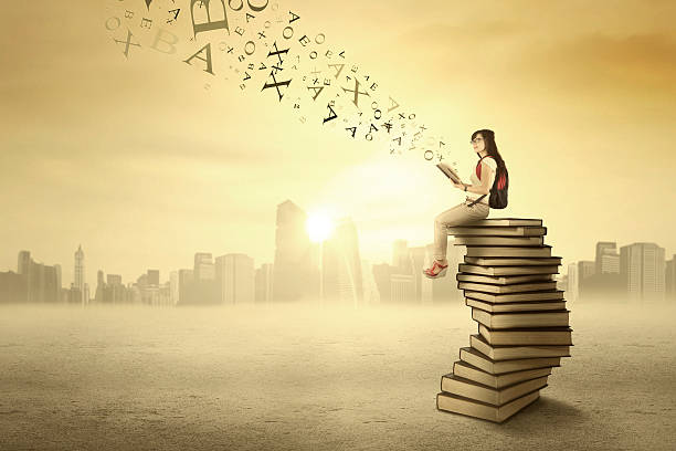 istock Student sitting on books outdoors 507237629