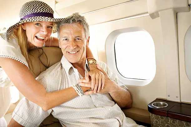 Smiling senior couple on an airplane heading overseas - portrait