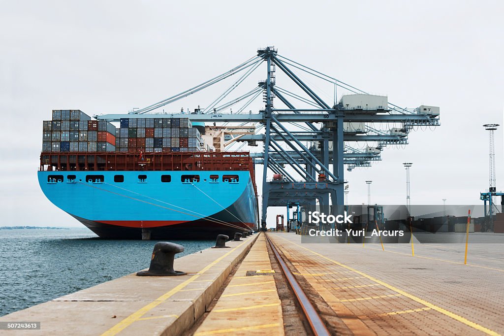 Getting ready to leave port A massive cargo ship moored at the harbor while being loaded with containers Freight Transportation Stock Photo