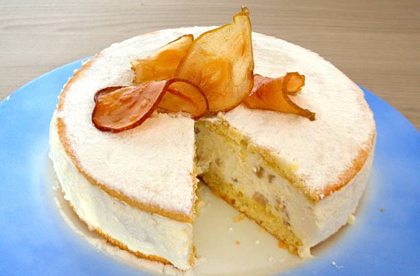 Ricotta and pere cake On round blue plate, white ricotta cake; inside the missing slice are visible small brown spots of pear and 2 layers of biscuit. The white surface is decorated with four transparent brown slices of pear. amalfi food stock pictures, royalty-free photos & images