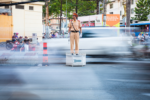 Ho Chi Minh City, Vietnam - November 19, 2015: Vietnamese policeman regulate traffic at the busy crossroad in Ho Chi Minh City, Vietnam.