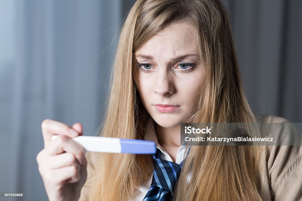 I hope it's false alarm... Stressed teenage girl looking on pregnancy test Pregnancy Test Stock Photo