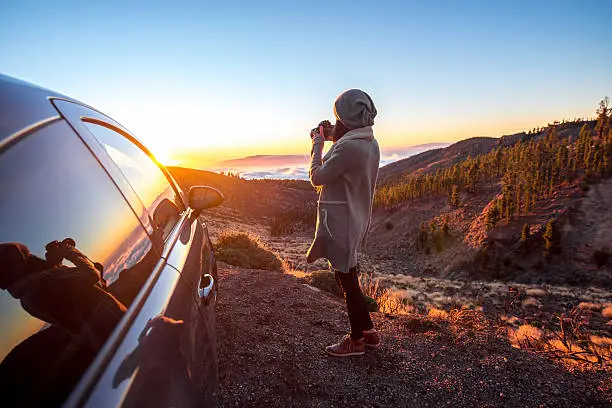 Photo of Woman photographing landscape standing near the car