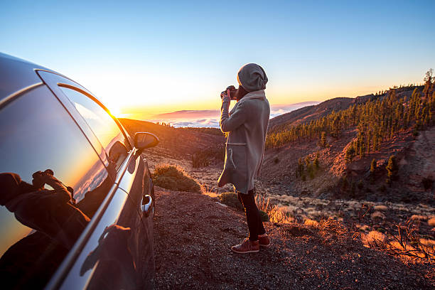 женщина, фотографирование пейзаж, стоя рядом с автомобиль - автомобиль фотографии стоковые фото и изображения