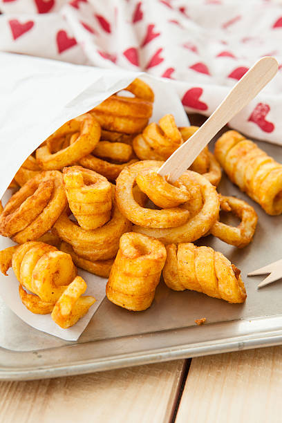 Spicy curly fries Spicy curly fries in white paper bag curly fries stock pictures, royalty-free photos & images