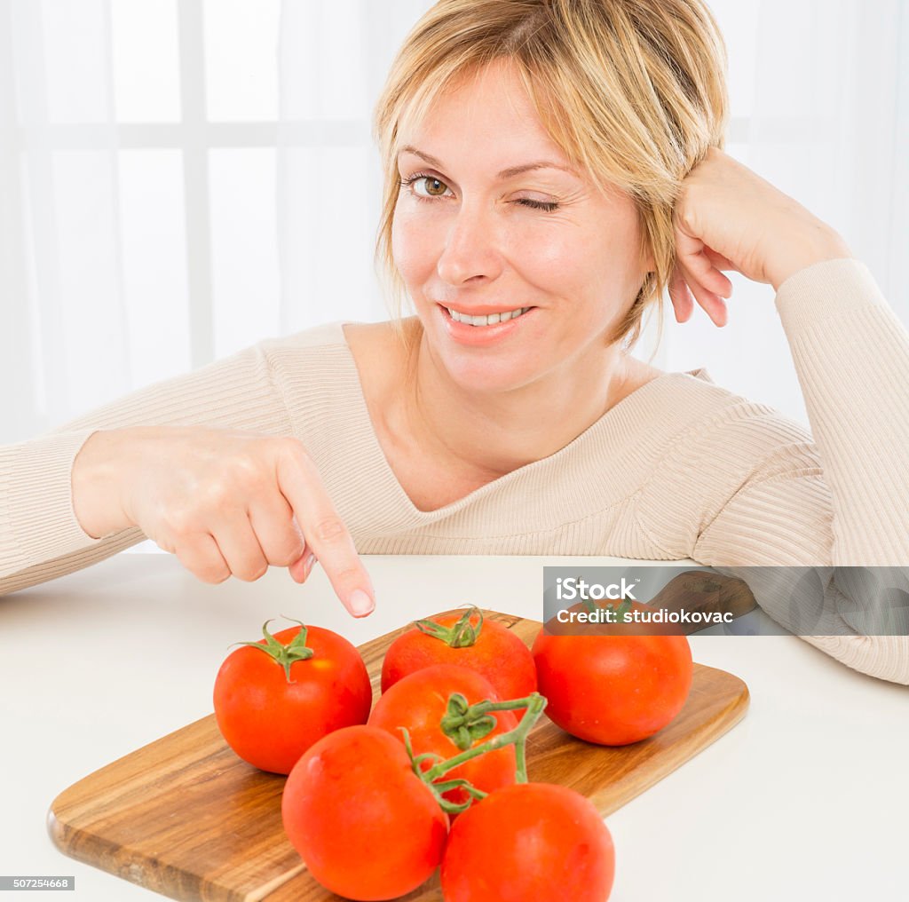 Woman and health. Smiling woman with tomatoes on plank winking at  the camera. 40-49 Years Stock Photo
