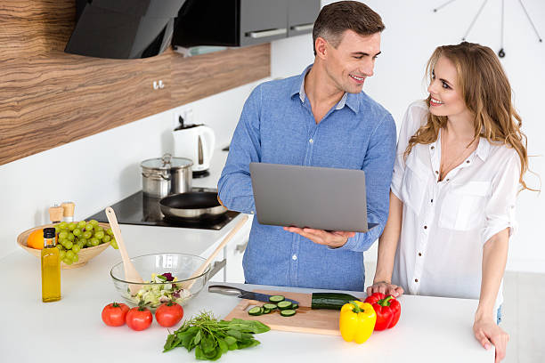 istock Happy couple using laptop and preparing vegetarian dishes 507255390