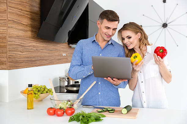 istock Beautiful smiling couple using laptop and making salad 507255440