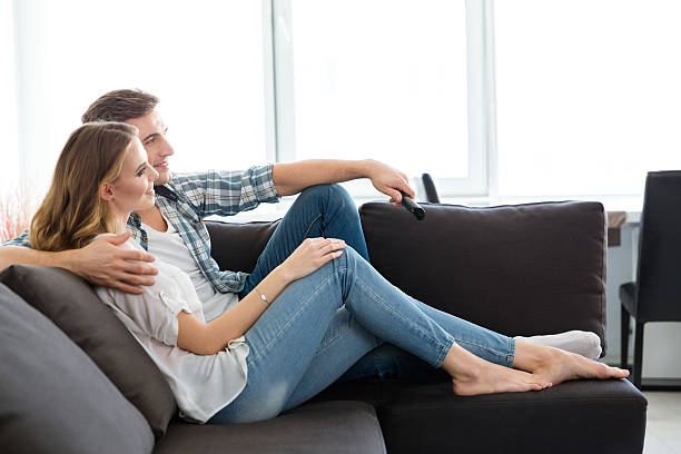 istock Happy couple sitting on sofa and watching TV 507256178