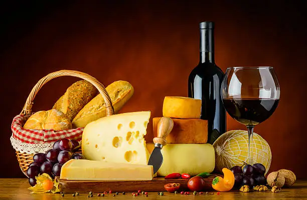 Cheese on Wooden chopping-board with Fruits and Vegetables and red wine with bun