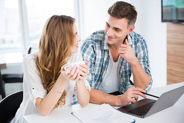 istock Smiling colleagues working with laptop and drinking coffee 507257046