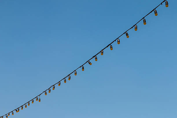 istock Closeup of the hanging light bulbs with blue sky 1 507258146