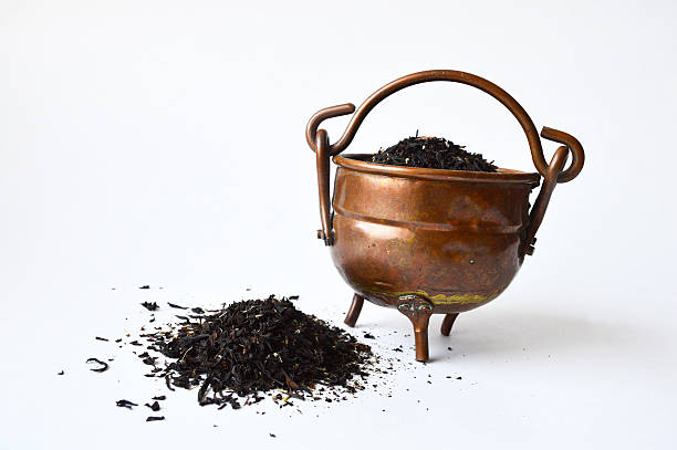 Copper pot of black tea with some spilled out Three-leg copper pot full of black tea with some tea spilled out three legged race stock pictures, royalty-free photos & images