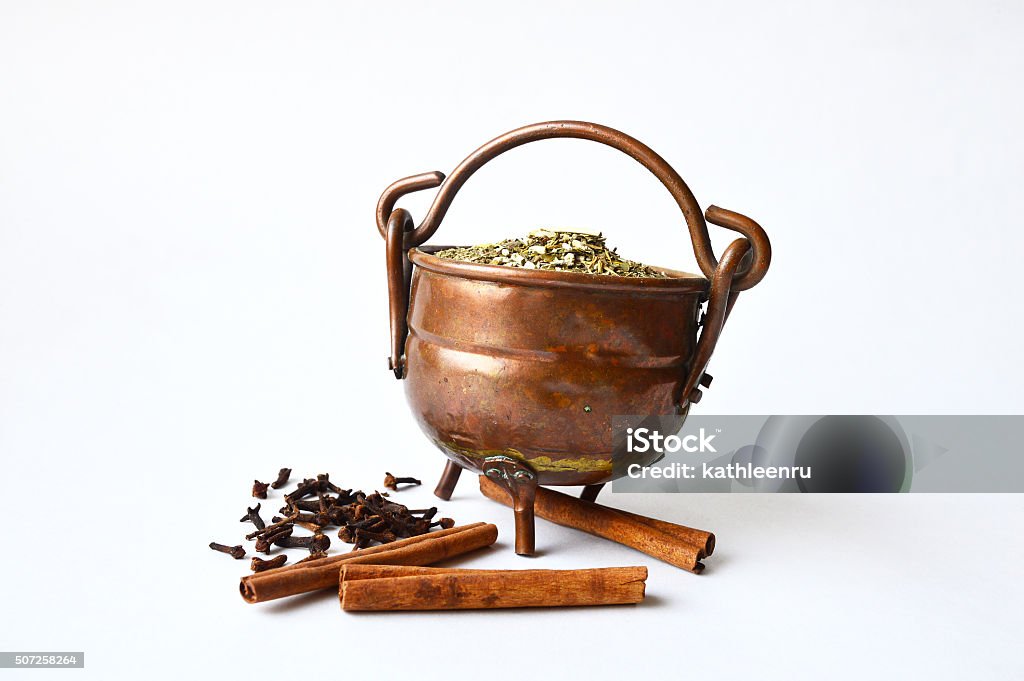 Copper pot of guarana with some cloves and cinnamon sticks Copper pot full of guarana with some cloves and three cinnamon sticks near it Ancient Stock Photo