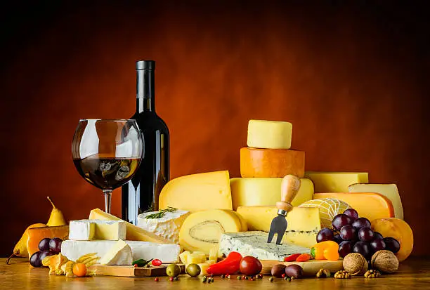 Red wine in glass and bottle with cheese and food in still life
