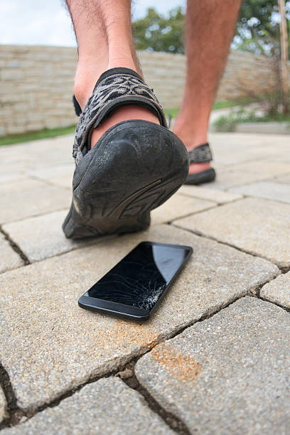 istock Man's foot stepping and smashing cell phone 507261074